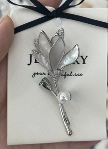 Macro detail of lily of the valley brooch with white shell petals and zircon stones