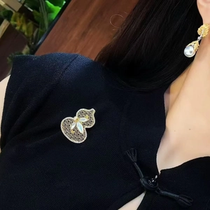 Close-up of 18K gold hollow gourd brooch and pearl earrings in elegant Chinese style