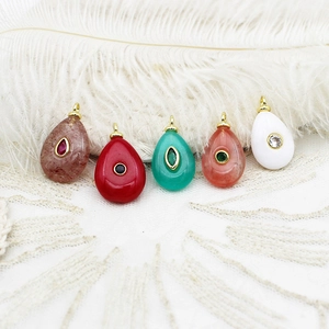 Macro detail of colorful teardrop pendants with gold loops on elegant feather background