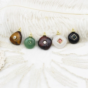 Collection of assorted natural stone geometric pendants with gold bails on white feathers