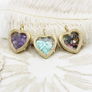Macro shot of heart-shaped gold pendants with colorful stones on white lace and feathers