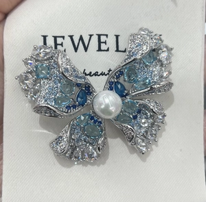 Détail de broche papillon avec cristaux dégradés bleus et incrustation de perle blanche