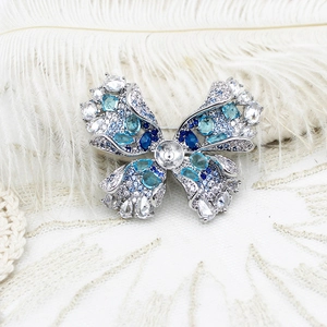 Élégante broche papillon en argent avec zircons bleus sur fond de dentelle blanche