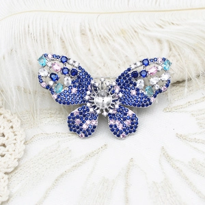 Détail d'une broche papillon en argent avec zircons multicolores et support de pierre centrale