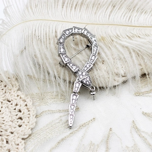 Broche serpent en argent avec zircons blancs sur un fond de plumes blanches douces