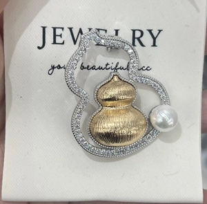 Detailed view of gourd brooch with mother of pearl and brushed 18K gold plating