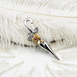 Detailed macro view of silver umbrella brooch with gold bow and yellow crystals
