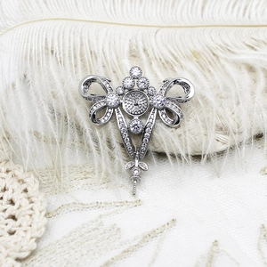 Detailed view of silver bow-shaped brooch setting with zircon pavé on white feathers