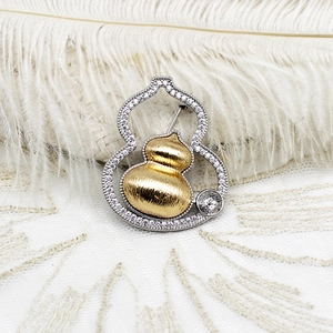 Macro detail of brushed gold gourd brooch with white diamond pavé on lace background