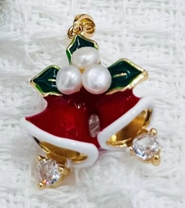 Macro detail of Christmas bell pendant with red enamel, holly leaves and white pearls