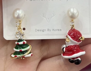 Detail of Christmas earrings featuring Santa Claus, a tree and white pearls with cubic zirconia