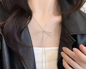 Gros plan d'un collier pendentif noeud argenté minimaliste sur un mannequin en veste cuir
