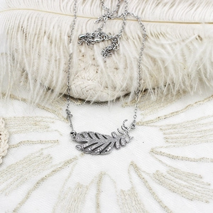 Vue macro d'un collier avec pendentif plume argenté orné de zircons blancs brillants