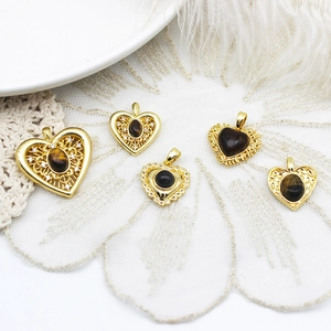 Dettaglio di ciondoli a cuore in occhio di tigre placcati oro 18k con filigrana vintage