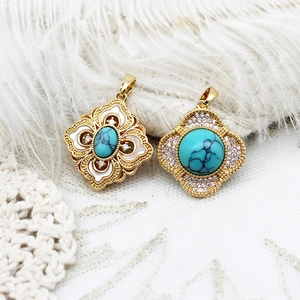 Detailed close-up of golden turquoise pendants with rhinestones on a white feather background