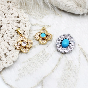 Detail of clover pendants with turquoise and purple stones on lace and feather background