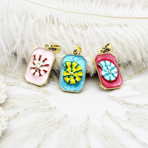 Detailed macro view of three colorful enamel spiral seashell pendants on lace