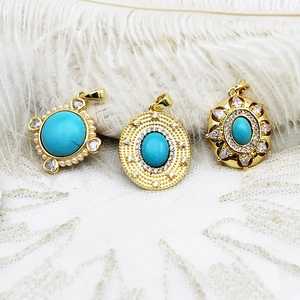 Detailed macro shot of vintage 18K gold turquoise pendants on white lace background
