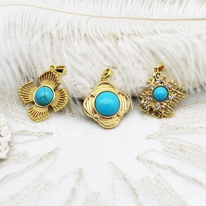Three gold pendants with turquoise stones on elegant white lace and feather background