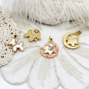 Golden balloon dog and unicorn charms with enamel inlay on a decorative background