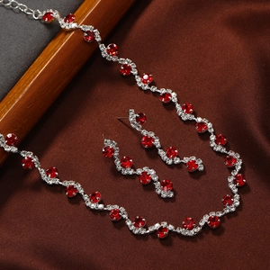 Elegant silver-toned necklace and earring set with vibrant red crystals on satin fabric