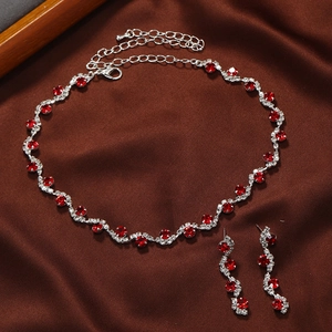 Elegant silver jewelry set with red crystal necklace and earrings on silk background