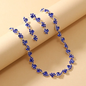 Detail view of blue rhinestone necklace and earring set on minimalist beige backdrop