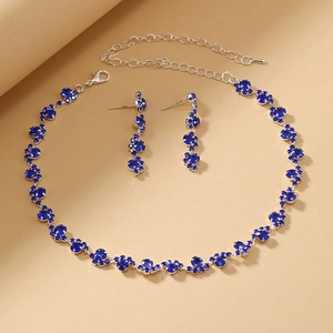 Detailed view of wave-style silver necklace and drop earrings with dark blue crystals