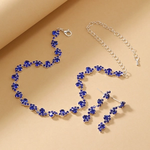 Detail view of necklace and long earrings set with deep blue rhinestones and silver chain