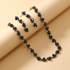 Detailed close-up of a black rhinestone necklace and earring set on a beige display
