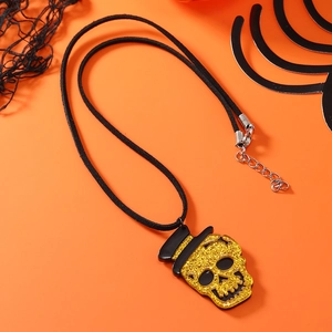 Detail der goldenen Glitzer-Totenkopfkette mit schwarzem Hut auf orangefarbenem Grund