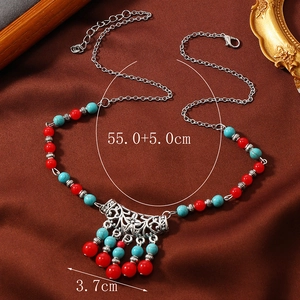Detail view of ethnic beaded necklace with silver floral pendant and colorful tassels