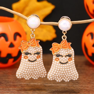 Detalle de pendientes de fantasma con perlas y lazo naranja con fondo de calabaza