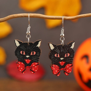 Detail of Halloween black cat earrings with red polka dot bow on rustic wood branch
