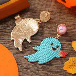 Detail of beaded Halloween ghost earrings with BOO sign on rustic wood backdrop