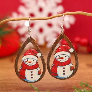 Primer plano de pendientes de madera con muñeco de nieve sobre fondo rojo navideño