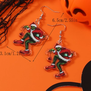 Gros plan de boucles d'oreilles Grinch de Noël mesurant 6,5 cm par 3,1 cm sur fond orange