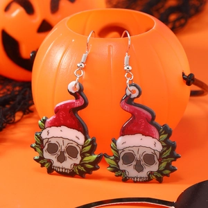 Boucles d'oreilles squelette avec bonnet de Noël sur décor festif de citrouille orange