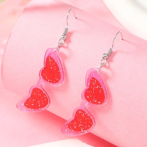 Orecchini a cuore in acrilico rosa con lenti glitterate rosse su sfondo rosa