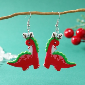 Creatieve kerst oorbellen met rode dinosaurus en groene stekels op een houten takje