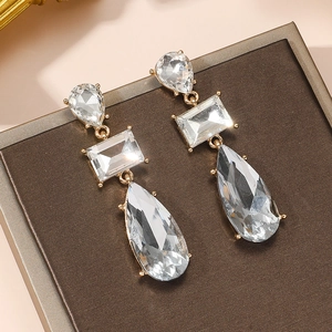 Détail de boucles d'oreilles dorées avec cristaux taillés en forme de larme et rectangle