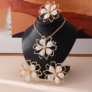Detail of floral jewelry set with white enamel and golden hollow petal design on black stand