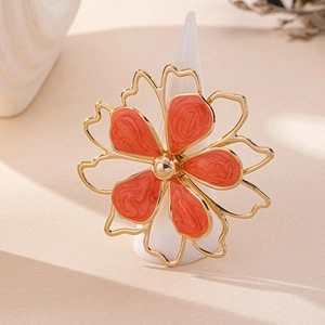 Detail of flower ring featuring orange enamel petals with marble texture and gold accents