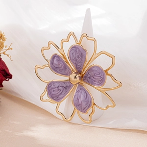 Detailed macro view of golden flower ring with purple marble enamel on a white cone stand