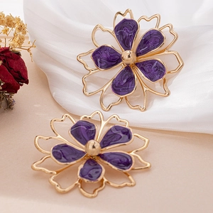 Detailed close-up of purple enamel flower earrings with golden metallic frames and stamen