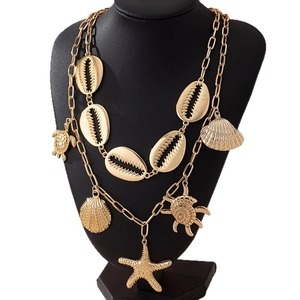 Collana dorata multistrato con ciondoli a stella marina e conchiglia su busto nero