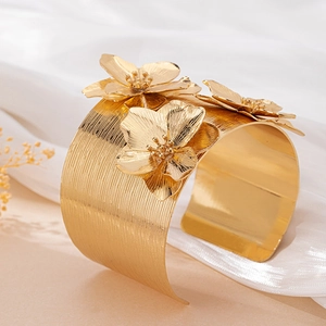 Bracelet manchette doré large orné de trois fleurs en métal sur fond en soie douce