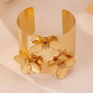 Détail d'un bracelet manchette doré à fleurs avec texture brossée et design floral 3D