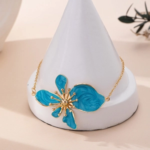 Dettaglio della cavigliera con fiori in smalto blu e petali dorati su espositore
