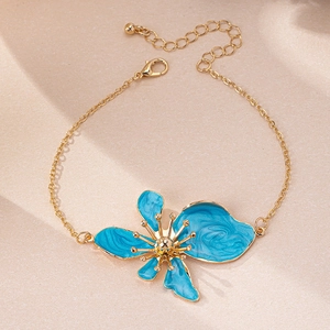 Dettaglio della cavigliera dorata con fiori in smalto blu e chiusura a moschettone